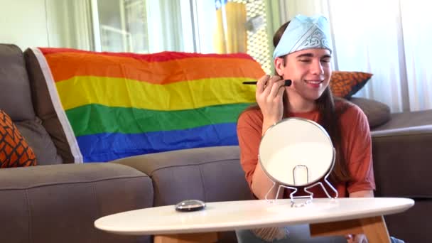 在家里 一个用刷子和镜子化妆的变性人坐在客厅的一面彩虹Lgbt旗旁边 — 图库视频影像