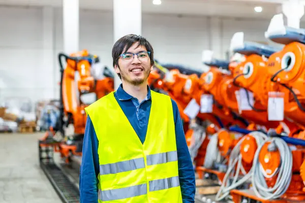 Portrait of a proud japanese chief engineer of a robotic arm production factory