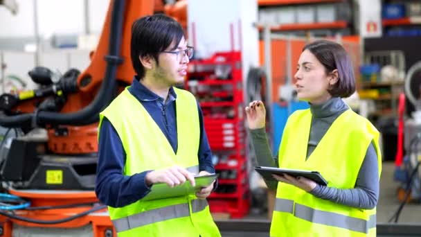 ロボットアーム工場の組立ラインを制御しながら笑顔の多文化男性と女性エンジニア — ストック動画