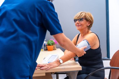 Kardiyoloji ofisinde kan basıncı testi sırasında hemşire ve olgun bir kadın.