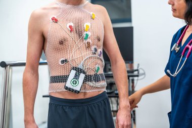 Kardiyolog, hastanede kardiyovasküler stres testi yapmak için bir hastaya ecg Holter takıyor.