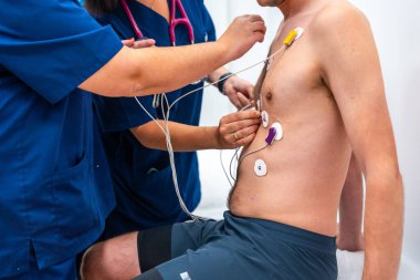 Cropped close-up photo of two cardiologists placing electrodes to a patient to perform a cardiovascular stress test clipart