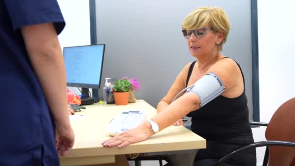 在心脏科办公室进行血压测试时的护士和成年妇女 — 图库视频影像