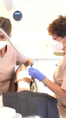 Diş kliniğinde bir kadının ağzını inceleyen teknisyen.