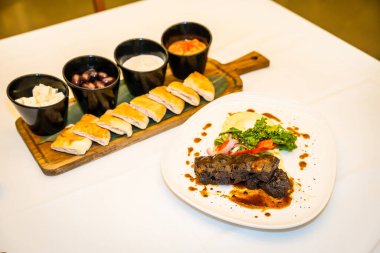 Lüks masa, pirzola ve aperatiflerle servis edilen ve yenmeye hazır ekmeklerle dolu güzel bir lokanta.