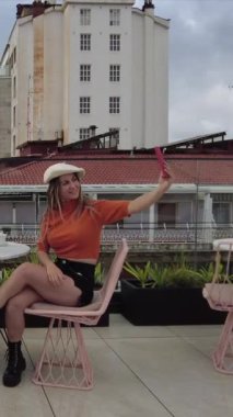 Arkadaşların şehir manzaralı bir kafeteryada cep telefonuyla selfie çekiyorlar.