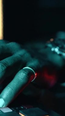 Konsantre ses mühendisi ya da yapımcı mavi LED ışıkla müzik kayıt stüdyosunda çalışıyor. Güneş gözlüklü zenci bir müzisyen.