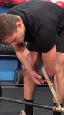 Kolu kesilmiş, spor salonunda ağırlık kaldıran tanınmayan engelli bir adam.