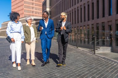 Çok ırklı iş adamlarından oluşan bir grup açık hava kahve molasında rahatça yürüyor.