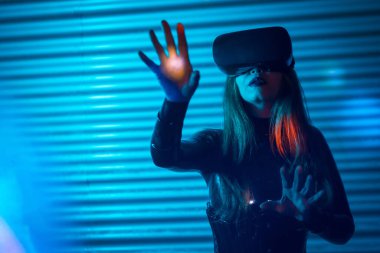 Kentsel alanda sanal gerçeklik simülatörü kulaklığı kullanan genç bir kadın