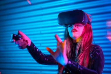 Sanal gerçeklik gözlüğü kullanan oyuncu neon ışıklarla dolu bir şehirde gece vakti