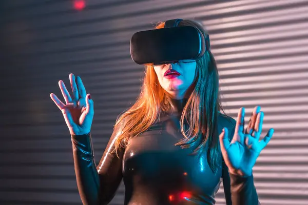 Surprised woman during an immersive game with Virtual reality goggles in an urban night space with neon lights