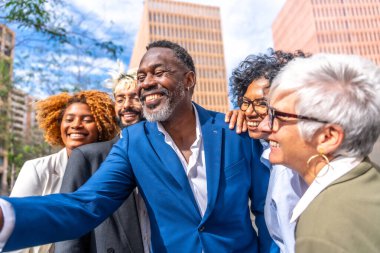 Olgun Afrikalı iş adamının dışarıda iş arkadaşlarıyla selfie çekerken yan görüntüsü.