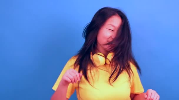 Studio Zdjęcie Niebieskim Tle Chińskiej Kobiety Używającej Słuchawek Uśmiechniętych Aparatu — Wideo stockowe