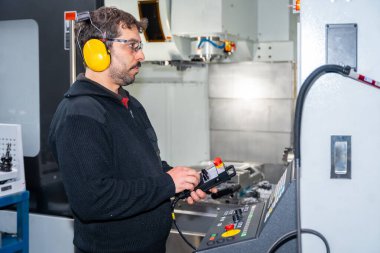 Cnc fabrikasında güvenlik teçhizatıyla çalışan bir mühendisin yan görüntüsü