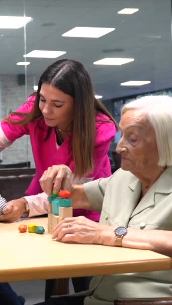 Милая Медсестра Унирофме Поощряет Пожилых Людей Играть Игры Навыков Доме — стоковое видео
