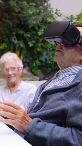 老人ホームの庭に座っているバーチャルリアリティゴーグルを使用した老人 — ストック動画