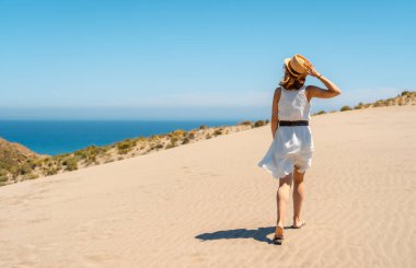 İspanya, Cabo de Gata 'da deniz manzaralı bir yolda yürüyen bir kadının arka görüntüsü.