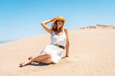 İspanya 'nın Cabo de Gata şehrinde rüzgarlı bir günde sahilde oturan zarif bir kadın.