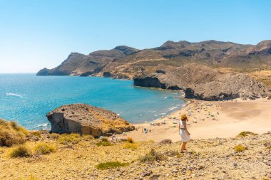 İspanya, Cabo de Gata 'da bir sahil yolunda bir tepenin kenarında yürüyen bir kadın.