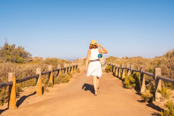 İspanya, Cabo de Gata 'da bir patika için sahilde yürüyen bir kadının arka görüntüsü.