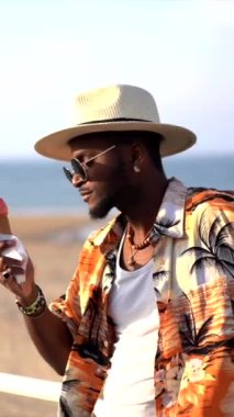 Zenci etnik adam plajda yaz tatilinin tadını çıkarıyor. Dondurma yiyor, gezintilerin tadını çıkarıyor.