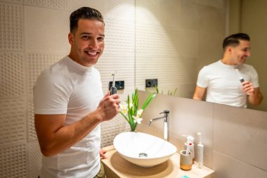 Banyoda dişlerini temizledikten sonra kameraya gülümseyen bir adam.