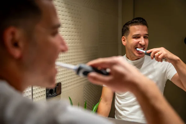 Reflection on the mirror of a Man brushing the teeth carefully at home