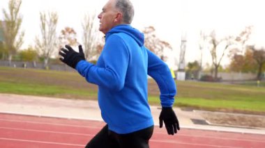 Atletizm pistinde koşan yaşlı bir adamın ön manzara portresi