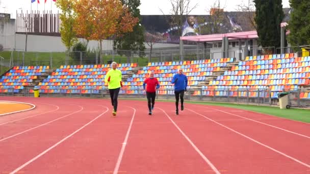 Widok Przodu Trzech Dojrzałych Mężczyzn Sportowych Biegających Torze Lekkoatletycznym — Wideo stockowe