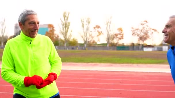 Glimlachende Oudere Man Met Sportkleding Opwarmen Een Track Field Winter — Stockvideo