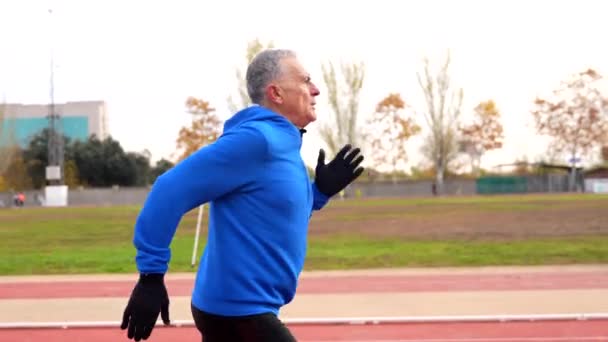 一位老人在田径运动跑道上努力跑的正面形象 — 图库视频影像