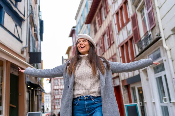 Free chic woman raising arms walking along a city visiting it and discovering it
