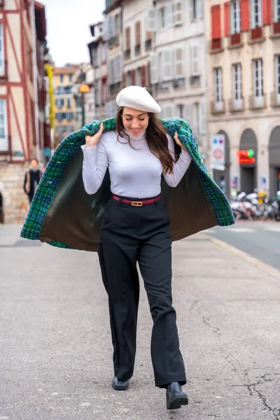 Vertical photo of a stylish woman dressing with coat while walking along the city