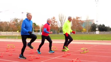 Kış aylarında atletizm pistine başlangıç blokları yerleştiren sportif kıdemli adam.