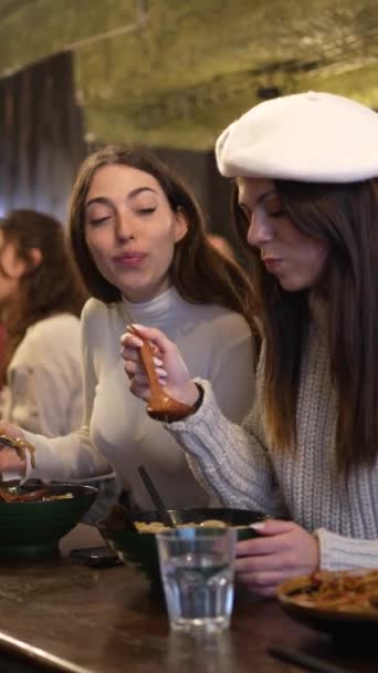 两个时尚女人在餐馆里吃拉面汤的垂直录像 — 图库视频影像