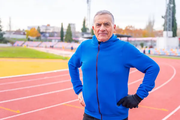 Portrait of a senior man with sportive warm clothes in an outdoor track