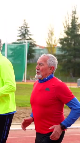 在田径运动中穿着五颜六色运动服的资深运动员一起跑步 — 图库视频影像