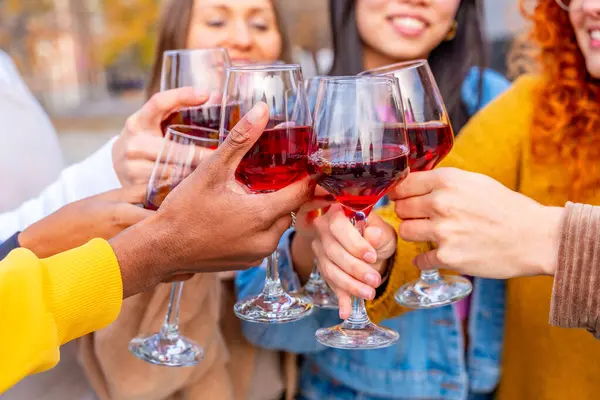 Close-up of friends celebrating and toasting with wine in the city street