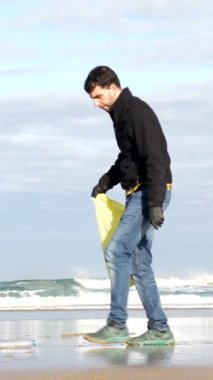 Man collecting garbage or plastic on the beach. Ecology concept, sea pollution