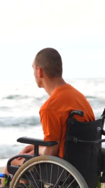 Tekerlekli sandalyede sırt üstü yatmış, kollarını açıp denizin ve doğanın özgürlüğünün tadını çıkaran engelli bir insan portresi.