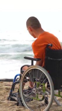 Tekerlekli sandalyede sakat birinin portresi. Deniz kenarında dalgın dalgın dalgın.