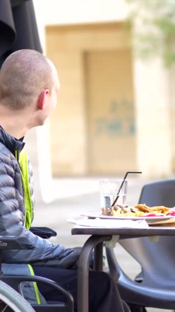 Людина Обмеженими Можливостями Їсть Терасі Ресторану Другом Який Допомагає Йому — стокове відео