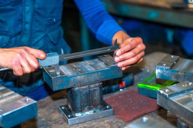 Kesik parmaklı bir operatör, bir CNC makine merkezi aracılığıyla yüksek teknolojili, sayısal kontrol atölyesinde değirmen kesicileri olan bir şirkette çalışıyor.