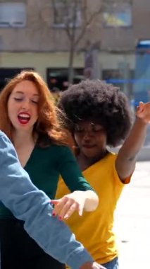 Şehirde dans eden, arkadaşlarıyla eğlenen çok ırklı genç arkadaşlar.