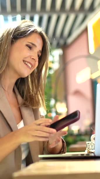 Mulher Sorridente Usando Laptop Conversando Com Celular Uma Cafeteria — Vídeo de Stock