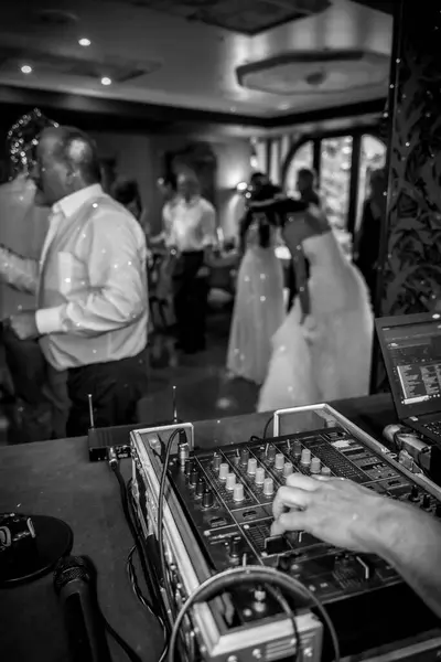 Hand of a DJ creating and regulating music on the DJ console mixer at a wedding