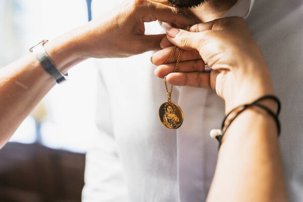 Detail of the groom's suit at the wedding, mother placing a religious brooch to give him luck at the ceremony