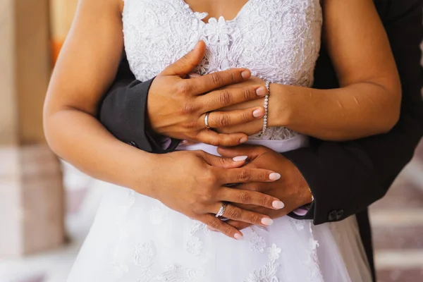 Black ethnic groom holding hands at a beautiful wedding and showing the rings, marriage portraits