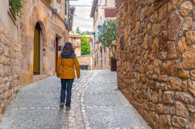 İspanya 'nın ortaçağ şehri Huesca' daki Alquezar Pyrenean köyünün sokaklarında yürüyen bir turist.